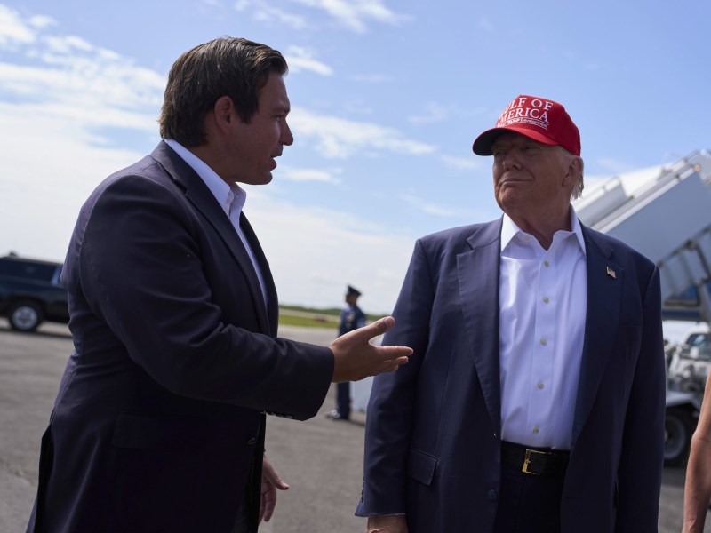 President Donald Trump listens as Florida Gov. Ron DeSantis speaks with reporters in July 2025. DeSantis’s takeover of New College previewed the kind of political control Trump is now trying to impose on universities nationwide.