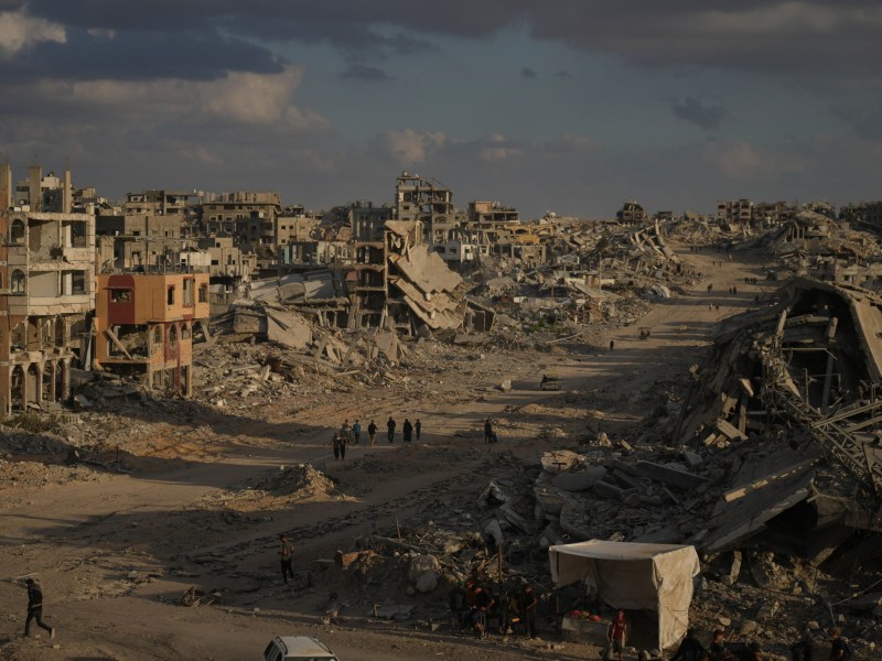 Palestinians walk among destroyed buildings in Gaza City, Sunday, Oct. 12, 2025, after Israel and Hamas agreed to a ceasefire in their war and the release of the remaining hostages.