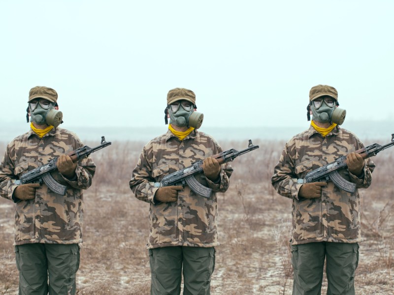 Soldiers with gas mask and automatic guns standing ready